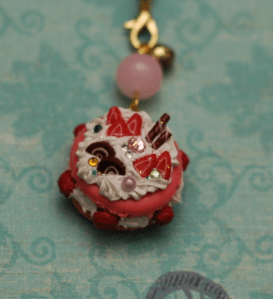 A pink macaron with white frosting and little cane slices. 